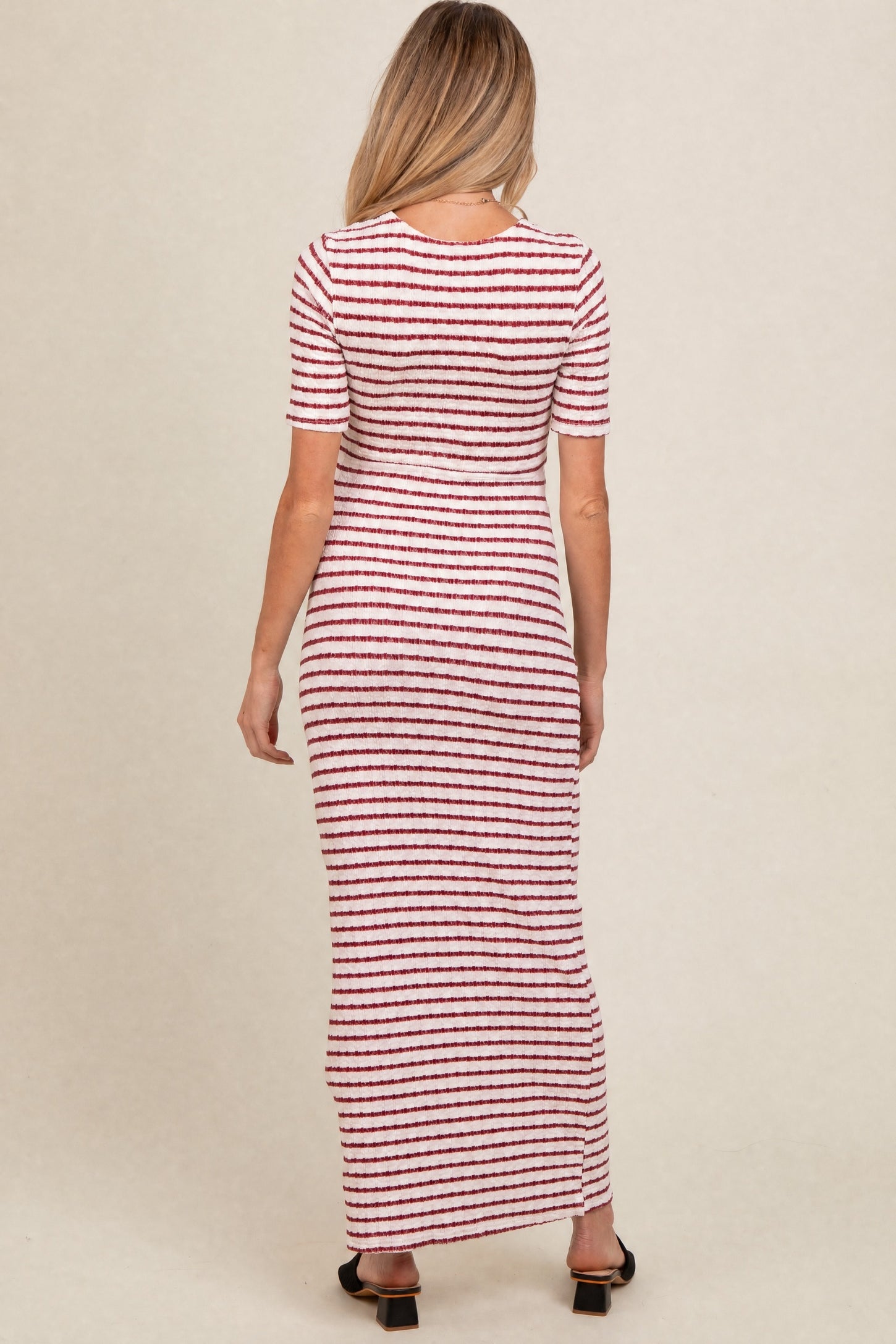 woman wearing a striped red and white long sleeve maternity dress, viewed from the back