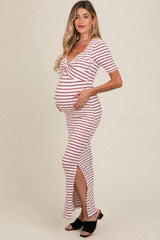 woman wearing a striped maternity maxi dress with a knot detail and side slit, showing her baby bump
