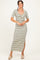 woman wearing a striped maxi dress with short sleeves and a knotted front detail, standing and smiling