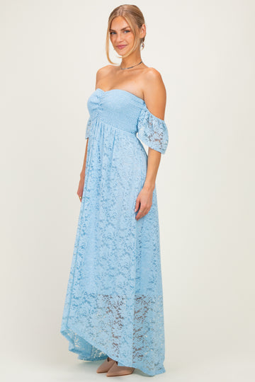 woman wearing a light blue off-the-shoulder lace maxi dress with short puff sleeves and a fitted bodice