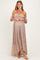 woman wearing a dusty rose off-the-shoulder lace maternity dress with a fitted bodice and flowing skirt, showing baby bump