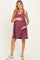 woman wearing a maroon striped maternity dress and holding her baby bump