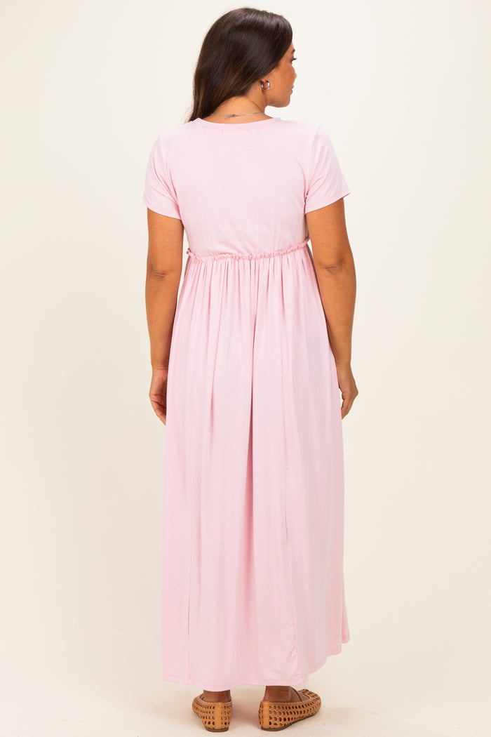 woman wearing a pink maternity maxi dress with short sleeves and an elastic waist, showing a pregnant belly from the back