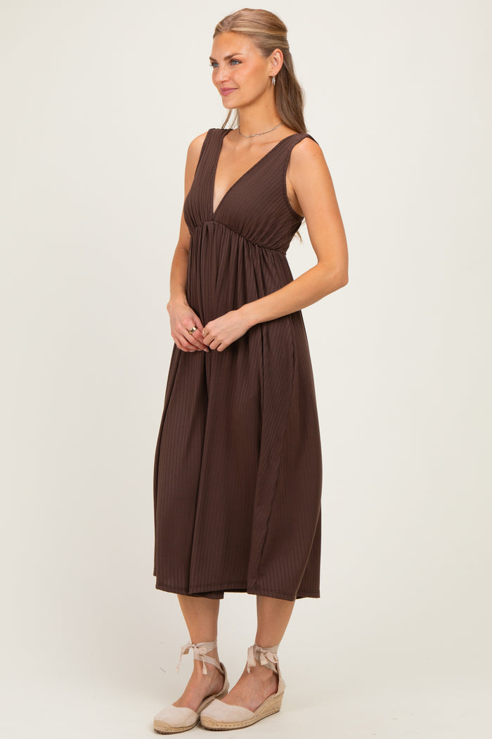 woman wearing a brown pleated midi dress with a deep v-neckline and a relaxed fit