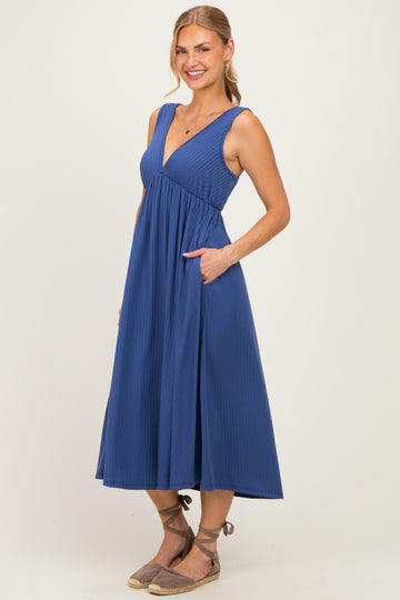 woman wearing a navy blue midi dress with a deep v-neck and pockets, styled with espadrille sandals