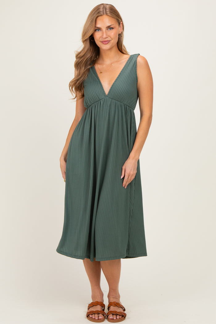 woman wearing a dark green pleated midi dress with a v-neckline and flared skirt