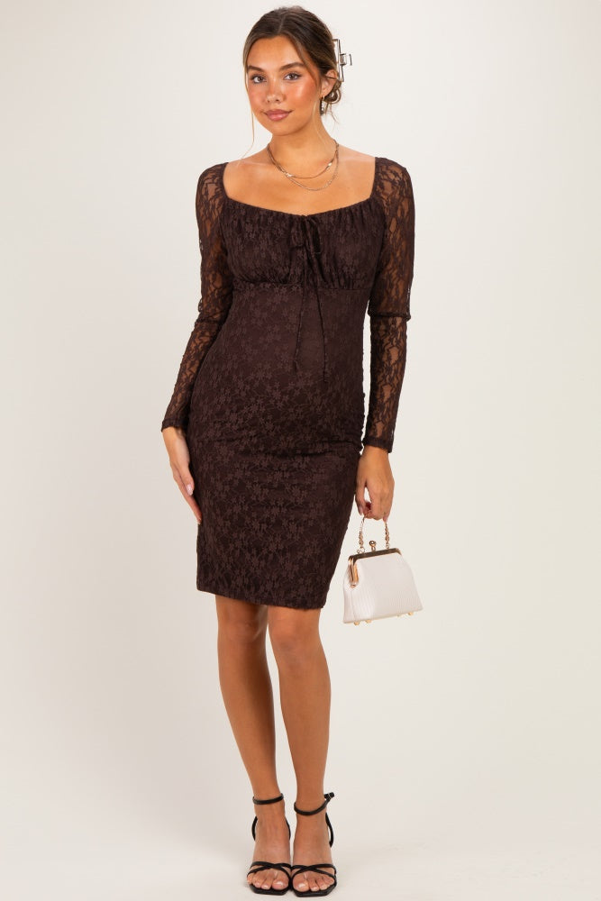 woman wearing a brown lace maternity dress with long sleeves and a fitted silhouette, holding a small white handbag