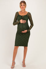 woman wearing a dark green lace maternity dress with long sleeves and a tie front, showing her baby bump