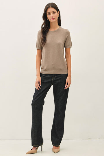 woman wearing a beige short sleeve knit top and high-waisted black jeans with pointed beige heels