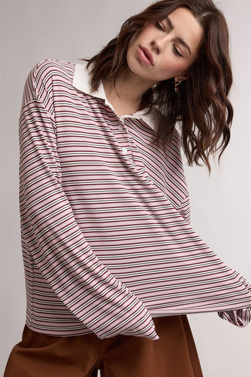 woman wearing a pink and white striped long sleeve polo shirt with a contrasting collar and relaxed fit