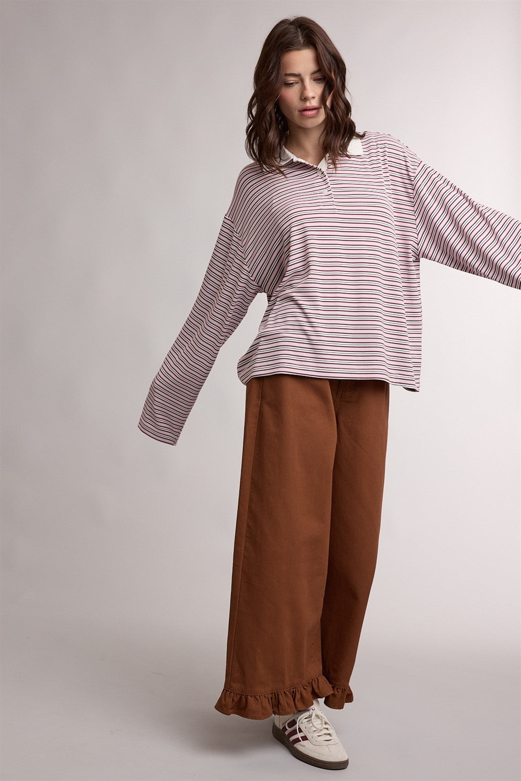 woman wearing a striped long sleeve oversized polo shirt with wide-leg brown pants and casual sneakers