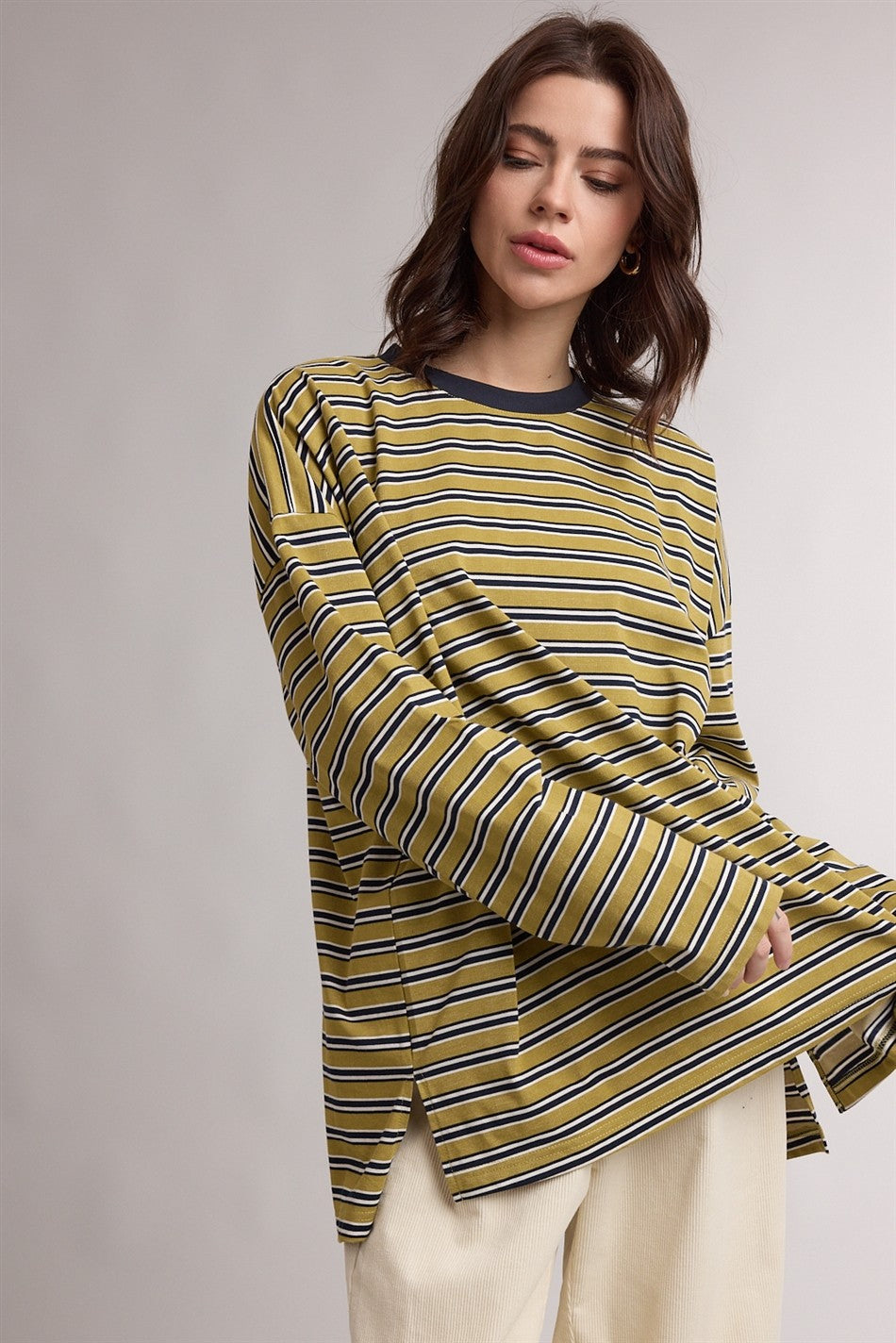 woman wearing a green and yellow striped long sleeve top with side slits and a relaxed fit