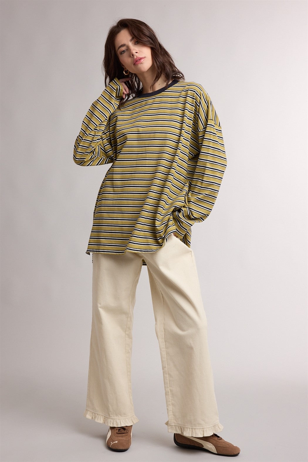woman wearing a striped oversized long sleeve top in yellow and black with cream wide-leg pants