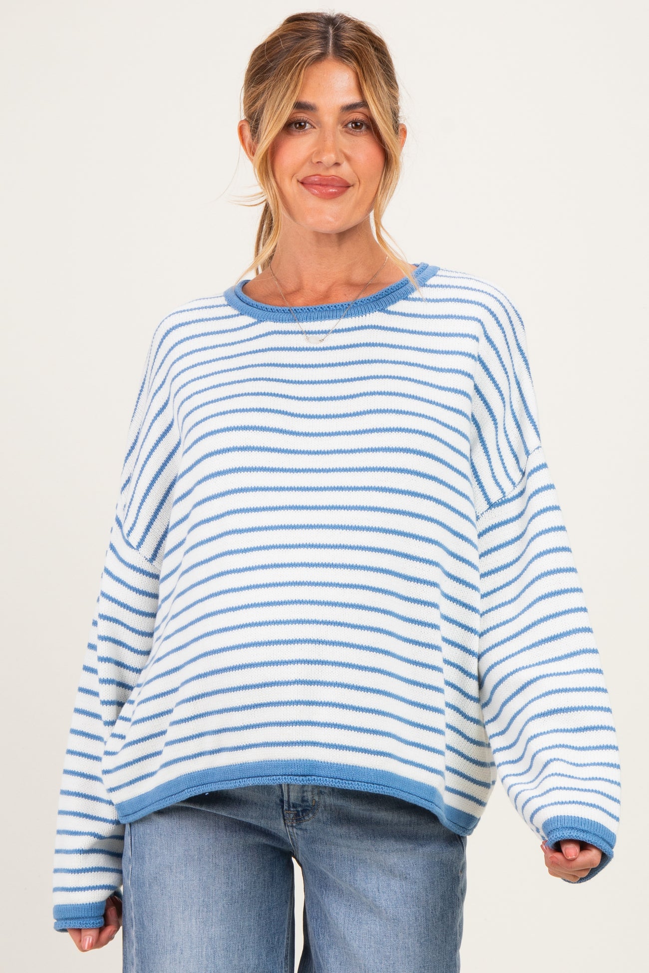 woman wearing a striped light blue and white oversized maternity sweater with a relaxed fit