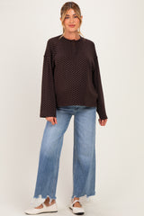 woman wearing a black polka dot maternity top with long sleeves and loose light blue maternity jeans