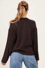 woman wearing a dark brown polka dot maternity top with long sleeves, shown from the back