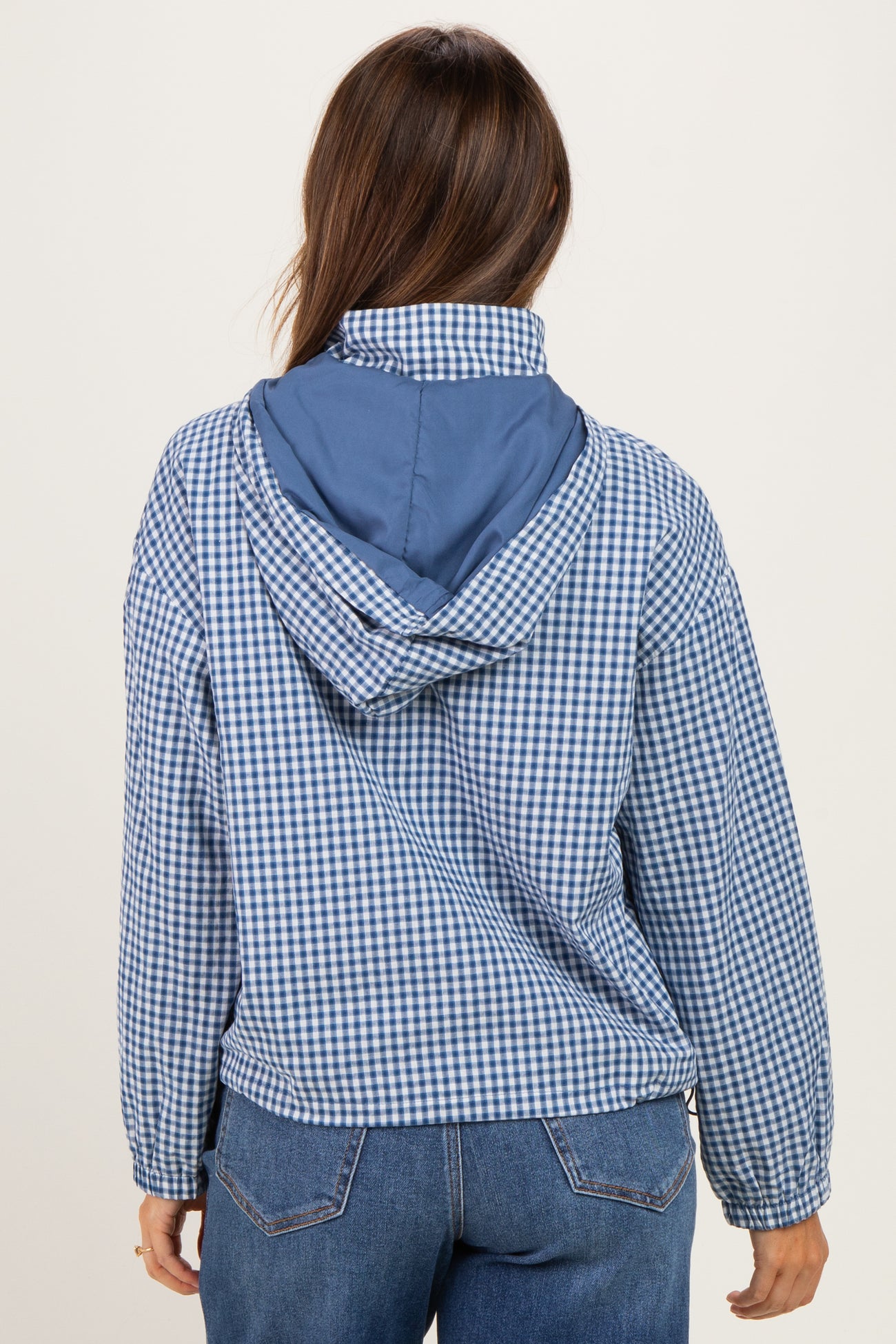 woman wearing a blue and white checkered maternity jacket, viewed from the back, with a blue hood