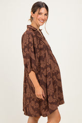 woman wearing a brown floral maternity dress with a loose fit and elbow-length sleeves, showing off her baby bump
