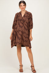 woman wearing a brown paisley print maternity dress with a loose fit and three-quarter sleeves, showing her baby bump