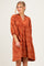 woman wearing an orange paisley print dress with a collar and puff sleeves