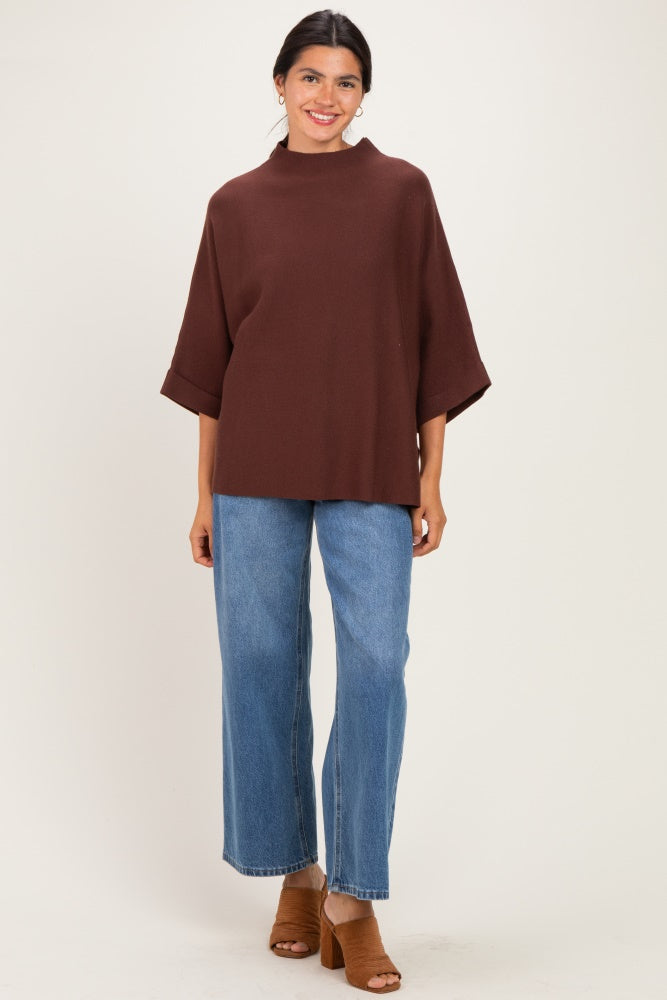 woman wearing a brown oversized top with half sleeves and high-waisted blue wide-leg jeans