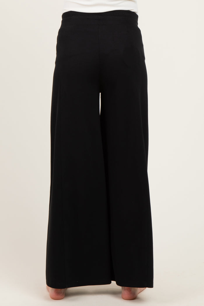 maternity wear black wide-leg pants displayed from the back, model wearing them with bare feet