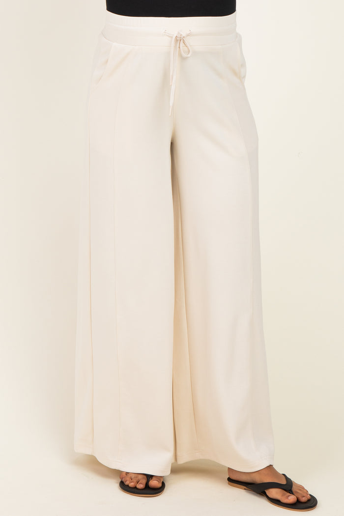 woman wearing cream wide-leg maternity pants with an elastic waistband and drawstring detail