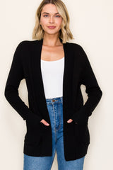 woman wearing a black open-front cardigan with pockets and a white tank top, styled with high-waisted jeans