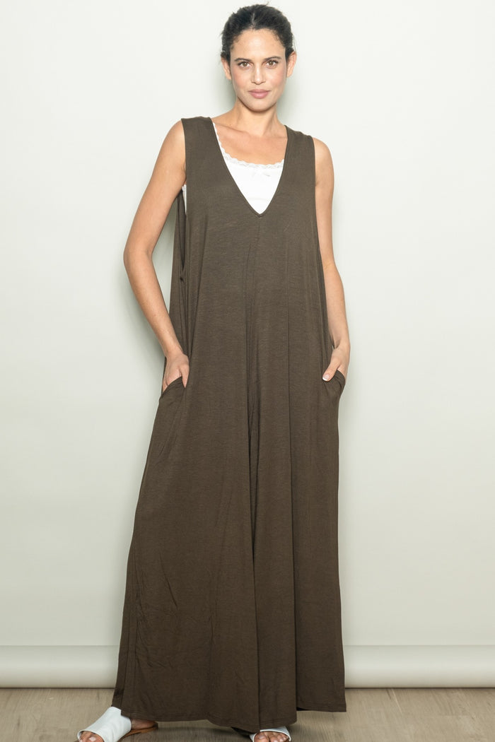 woman wearing a brown sleeveless maxi dress with side pockets and a v-neckline
