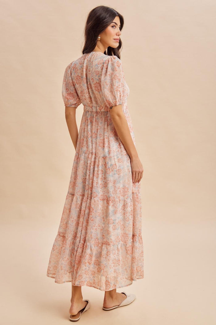 woman wearing a floral maxi dress with puff sleeves and a tiered skirt, viewed from the back