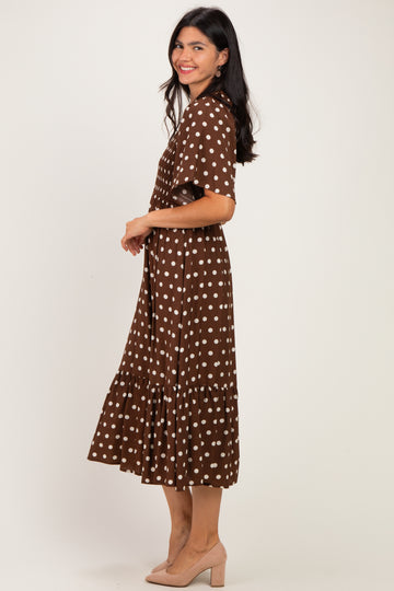 woman wearing a brown polka dot midi dress with a tiered skirt and short sleeves, standing in profile