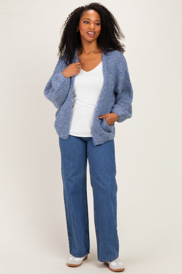woman wearing a light blue oversized knit cardigan over a white top and blue wide-leg jeans