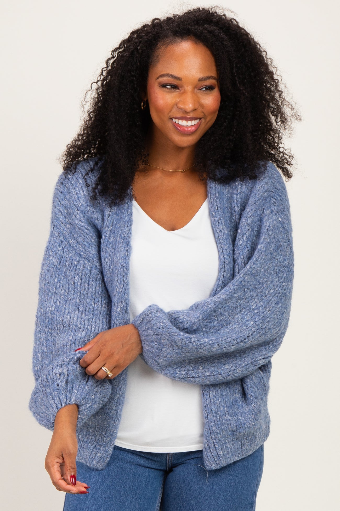 woman wearing a light blue oversized cardigan over a white top with a relaxed fit and curly hair