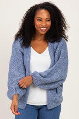 woman wearing a light blue oversized cardigan over a white top with a relaxed fit and curly hair