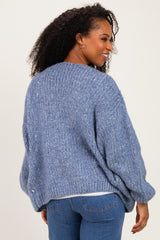 woman wearing a blue oversized chunky knit sweater, viewed from the back, styled with denim jeans