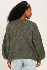 woman wearing a green chunky knit sweater with balloon sleeves, viewed from the back, paired with light denim jeans