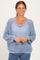 woman wearing a light blue open knit sweater with a relaxed fit and scoop neckline, smiling against a neutral background