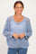 woman wearing a light blue open knit sweater with a relaxed fit and scoop neckline, smiling against a neutral background