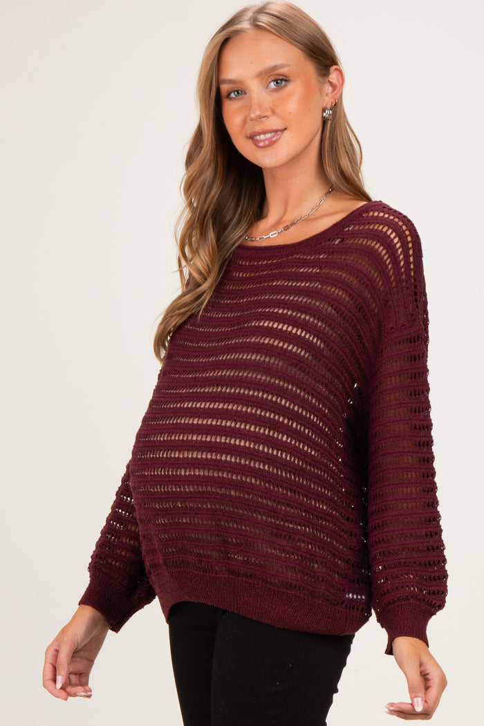 woman wearing a burgundy maternity sweater with open knit design and visible baby bump
