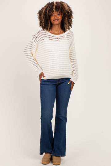woman wearing a cream striped maternity sweater with a relaxed fit and blue flared maternity jeans