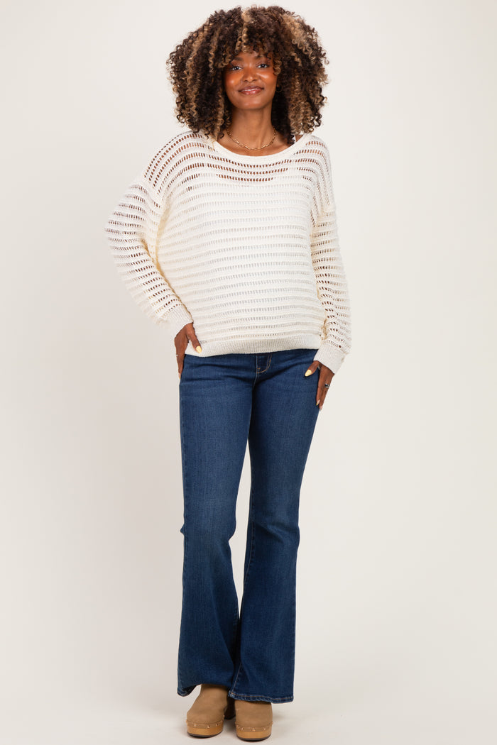 woman wearing a cream striped maternity sweater with a relaxed fit and blue flared maternity jeans