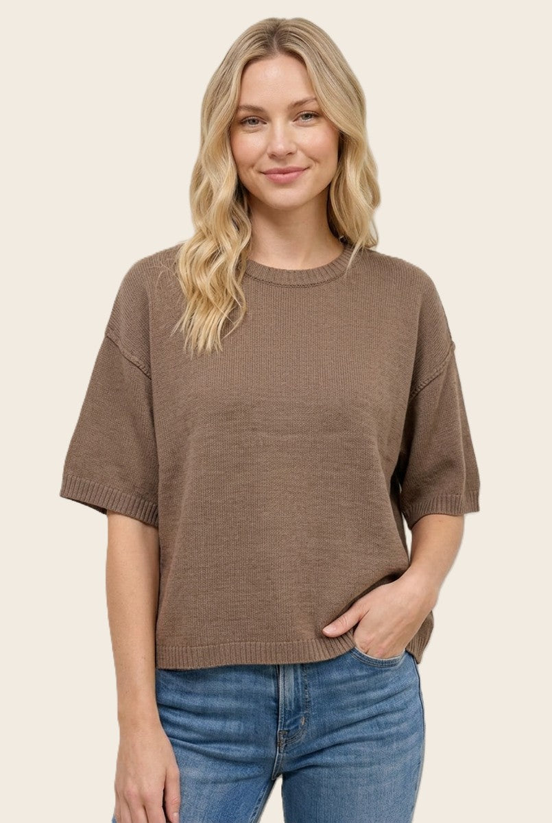 woman wearing a brown short sleeve sweater with a relaxed fit and light blue jeans