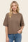 woman wearing a brown short sleeve sweater with a relaxed fit and light blue jeans
