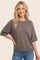 woman wearing a relaxed fit brown short sleeve sweater with a rounded neckline and a casual pose