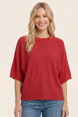 woman wearing a red oversized short sleeve sweater with a relaxed fit and smiling