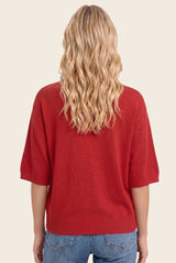 woman wearing a red short sleeve sweater with a relaxed fit and back view of wavy blonde hair