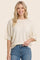 woman wearing a cream oversized sweater with short sleeves and a relaxed fit, paired with blue jeans