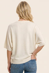 woman wearing a cream oversized knit sweater with half sleeves, viewed from the back