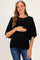 woman wearing a black short sleeve maternity sweater and gently holding her baby bump