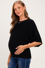 woman wearing a black short sleeve maternity sweater and holding her baby bump